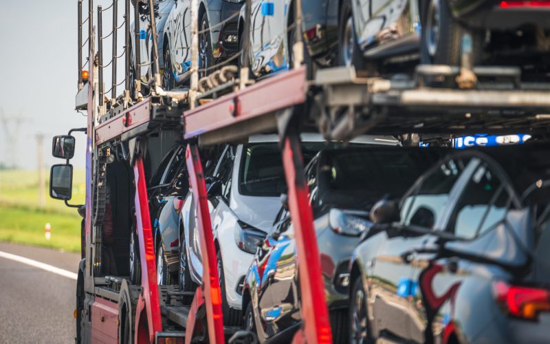 Moving Brand New Vehicles From Factory to Dealerships Across Country. Car Carrier Semi Truck Trailer on the Road. Automotive and Transportation Industry Theme.